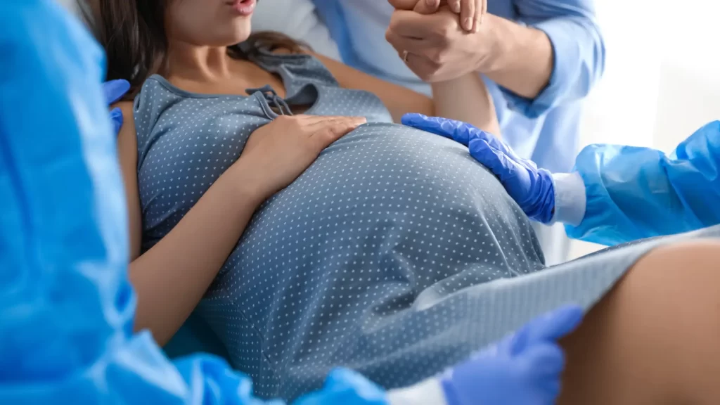 Doctor assisting a pregnant woman during labor in a medical setting.