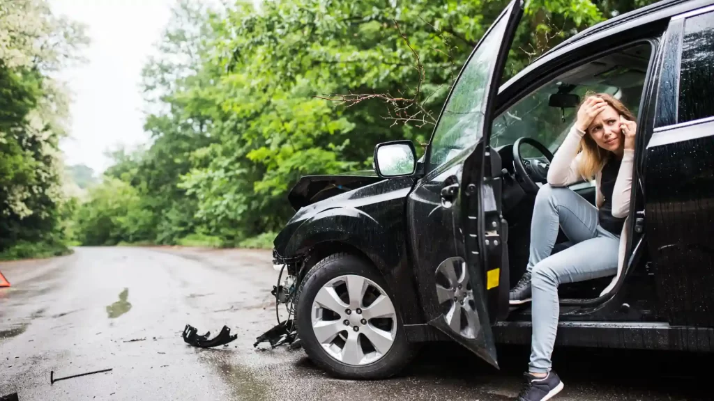 Damaged black car on roadside after accident.