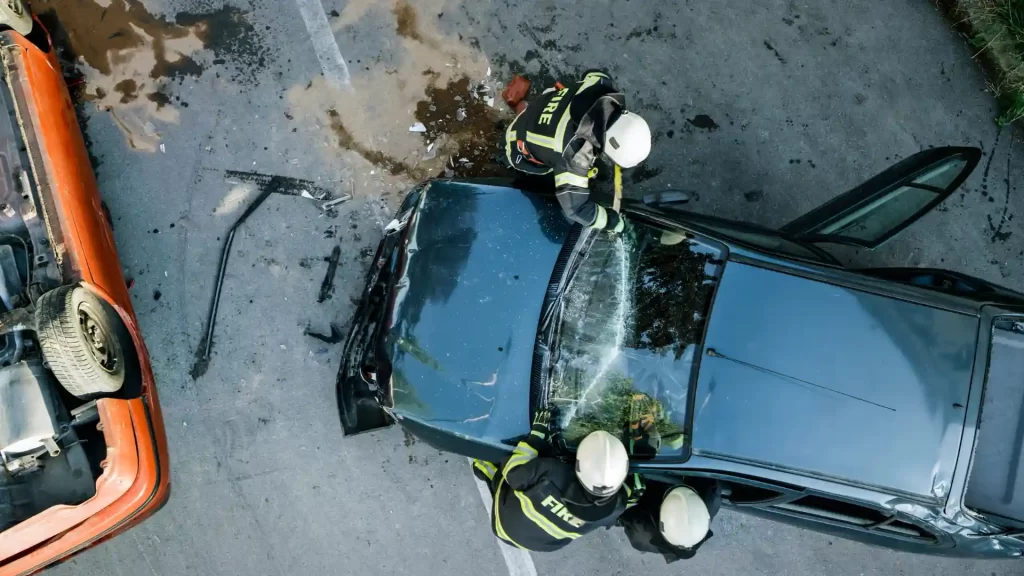 Firefighters rescuing from crashed car with shattered windshield