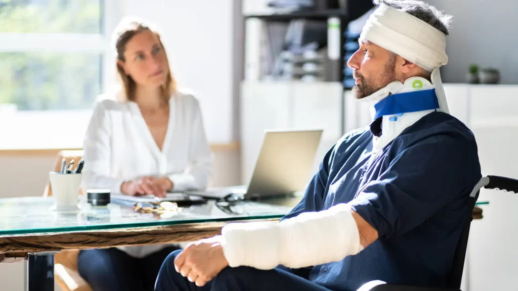 Injured man with neck brace and arm cast meeting lawyer.